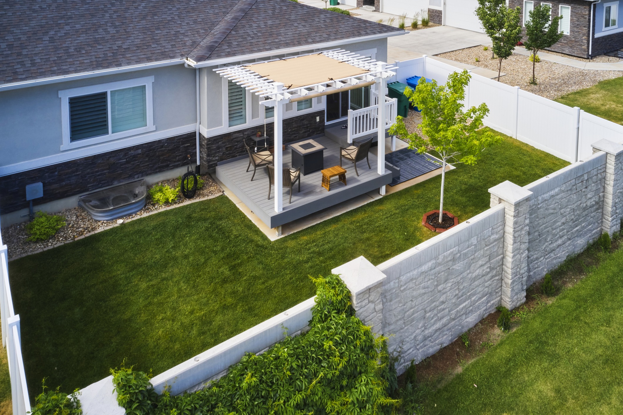 A beautiful outdoor living space is possible even in small backyards like this one, complete with a decorative fence and pergola.