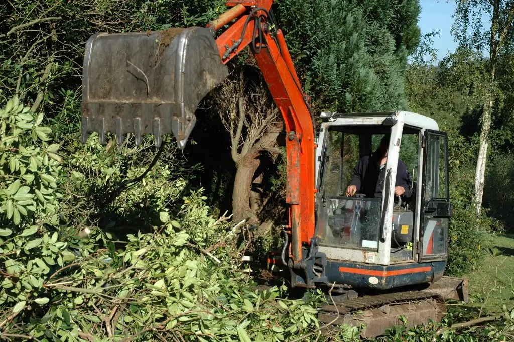 A landscape technician uses an excavation tool to clear the land for a new homeowner.