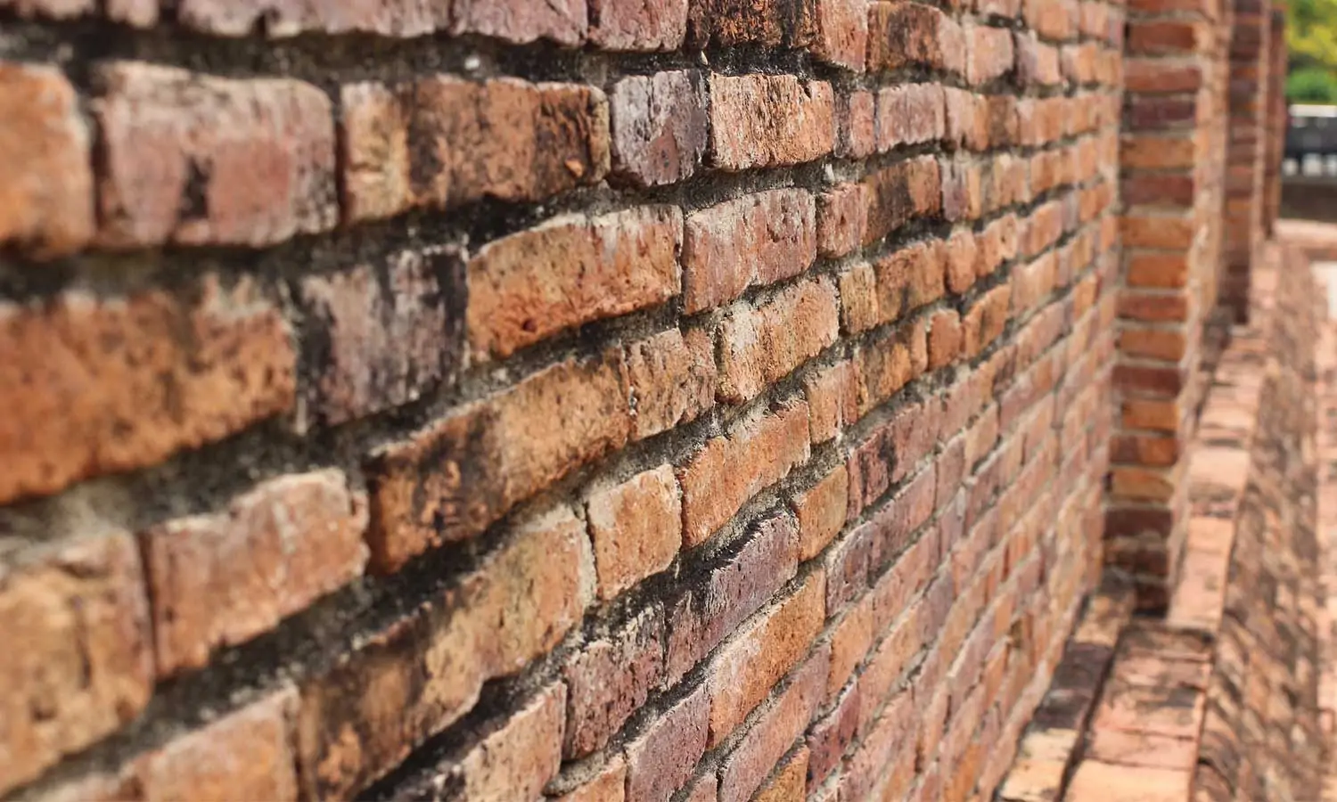 Red brick wall with structural damage above concrete foundation in Long Island