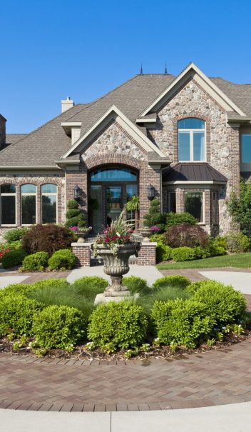 A luxury home is never complete without luxury landscaping to match, as illustrated by this manor's elegant entryway complete with well-tended decorative plants.